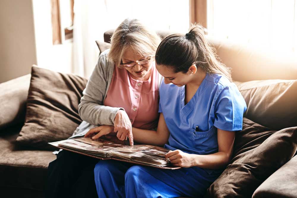 Caregiver and senior woman bonding over a photo album in Hopkinsville, KY