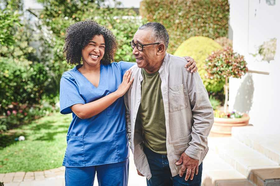 Caregiver walking outdoors with smiling senior man in Hopkinsville, KY