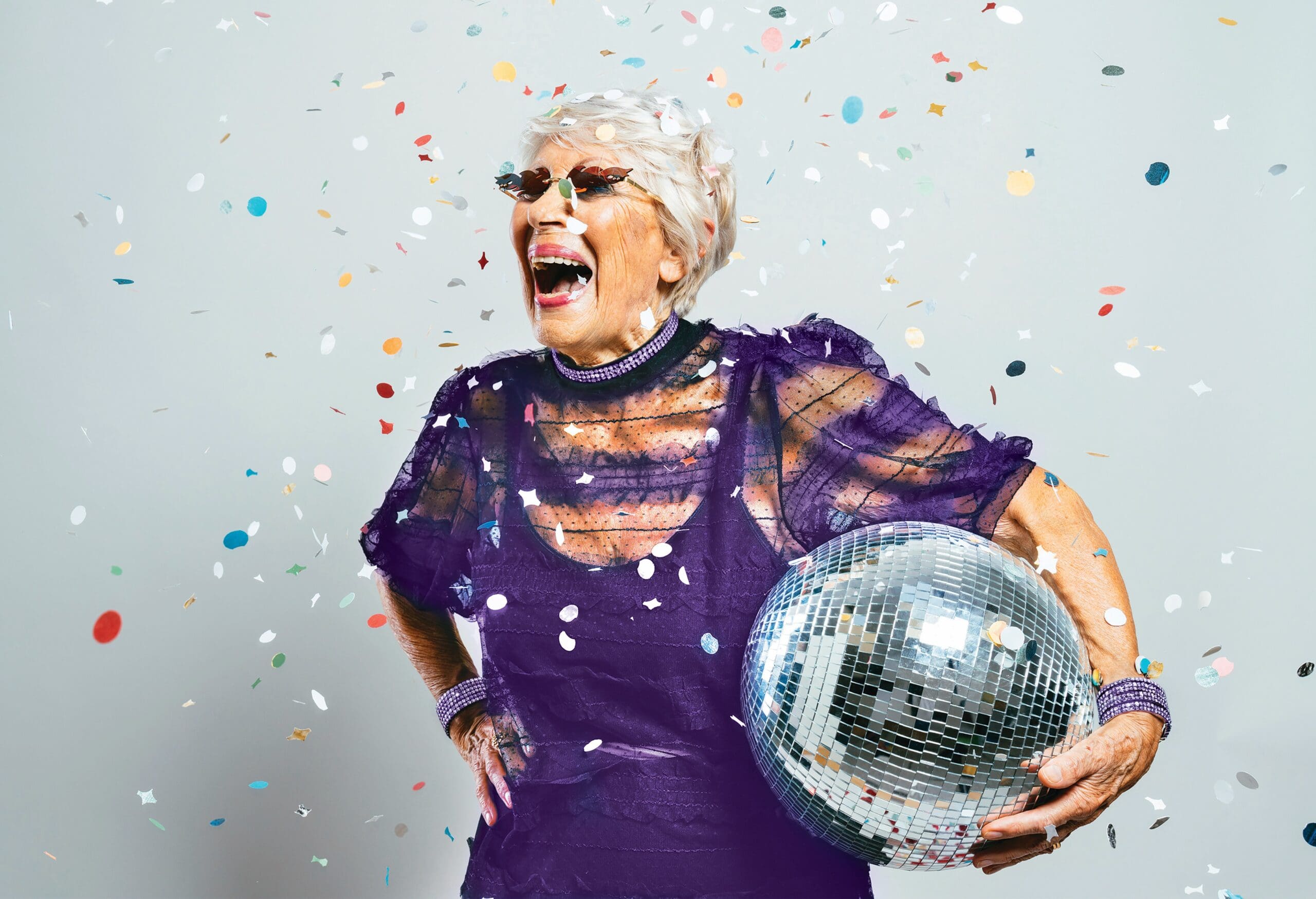 Joyful older woman celebrating with confetti and disco ball at Charter Senior Living of Hopkinsville in Hopkinsville, KY.