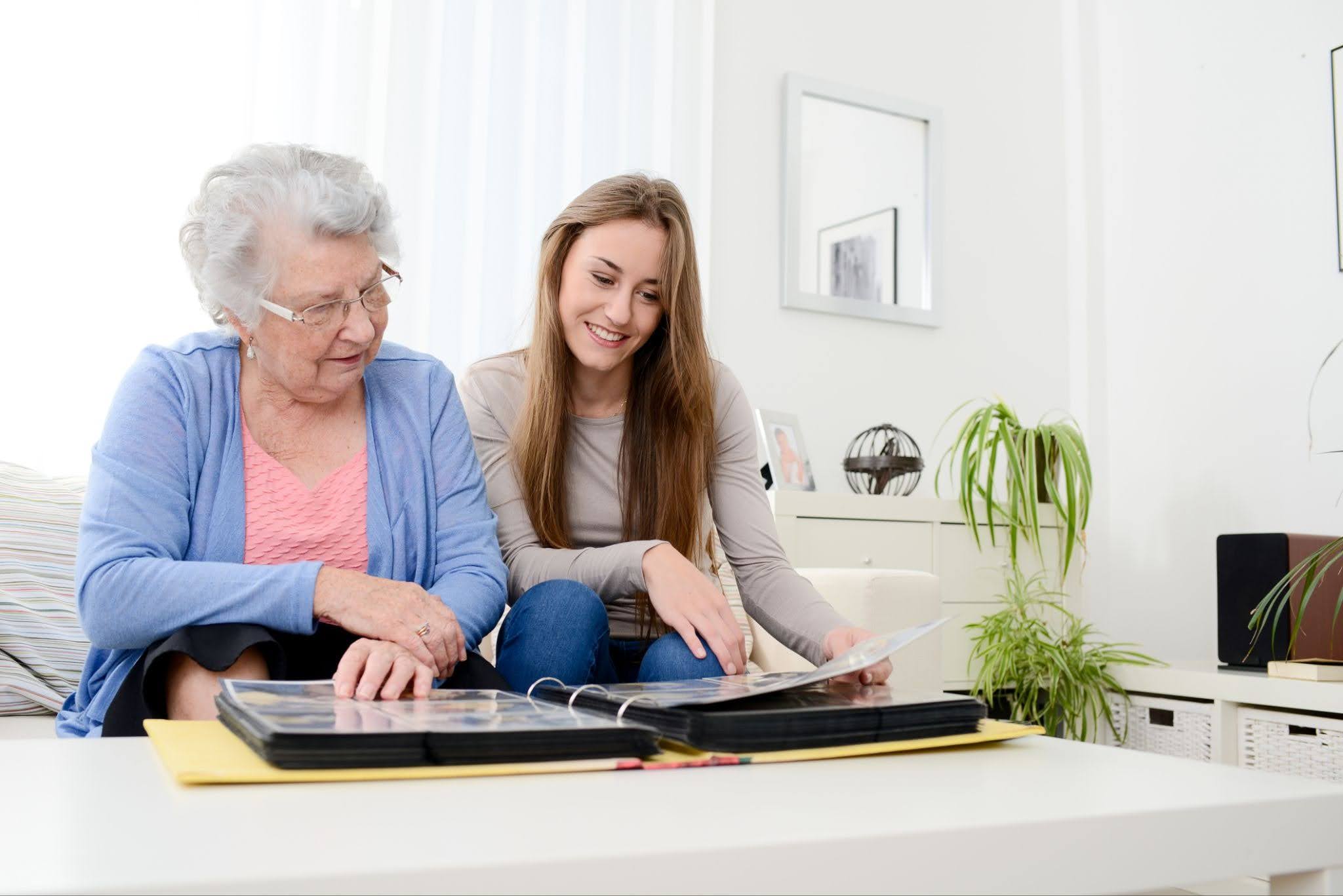 An adult daughter looking a photo album with her elderly mom and talking about how to help a parent with dementia in hopkinsville KY.